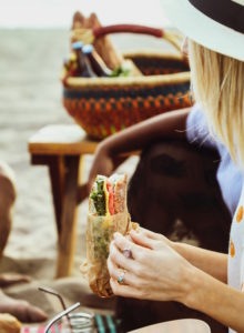 girl having a picnic eating a sandwich on the beach