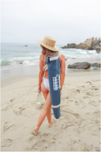 girl walking on beach with beach umbrella in carrying case