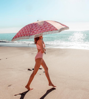 girl walking on beach with thalia beach umbrella