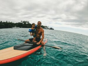 Dad and kid on a surfboard in the water